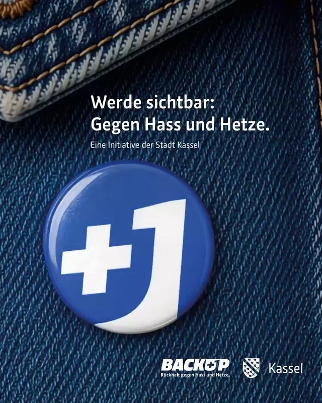 Logo "BACKUP" mit Claim "Rückhalt gegen Hass und Hetze" und Ansteck-Pin mit "+1" auf blauem Jeansstoff.
