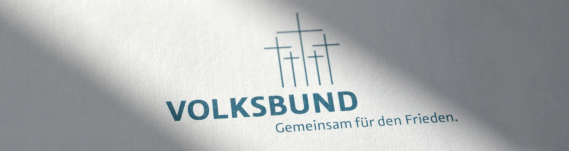 Logo des Volksbund Deutsche Kriegsgräberfürsorge e.V. mit dem Schriftzug "VOLKSBUND" und dem Slogan "Gemeinsam für den Frieden.