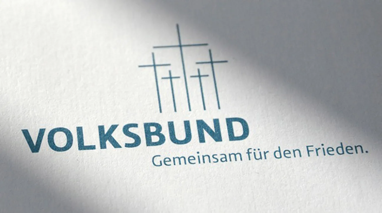 Logo des Volksbund Deutsche Kriegsgräberfürsorge e.V. mit drei Kreuzen und dem Slogan &quot;Gemeinsam für den Frieden.&quot; auf weißem Papier.